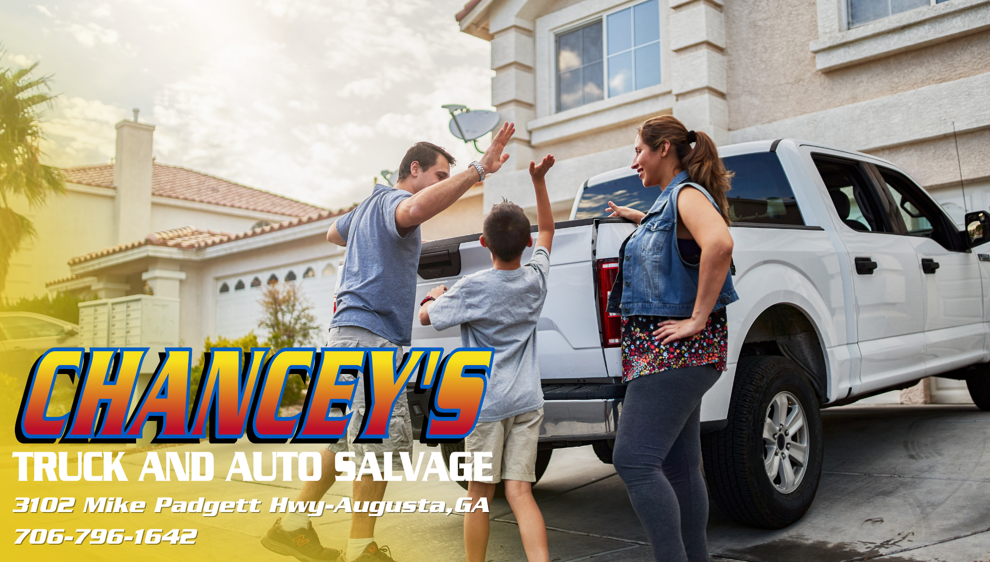a family stands outside of a pickup truck in a driveway