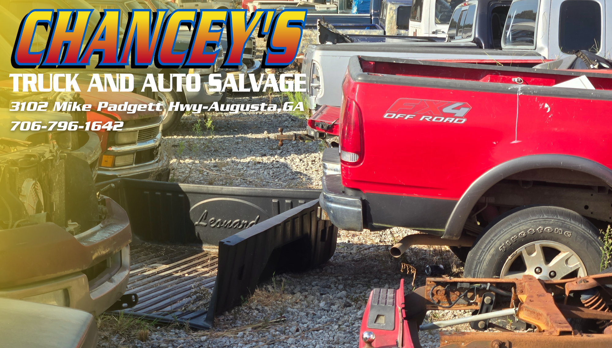 various salvage vehicles sit inside of a salvage yard