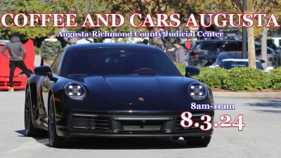 a black muscle car sits in a parking lot for a car show