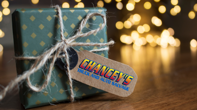 christmas chanceys a christmas gift warpped in a natural paper with gift tag displaying the name of chancey's sits on the floor in front of christmas lights